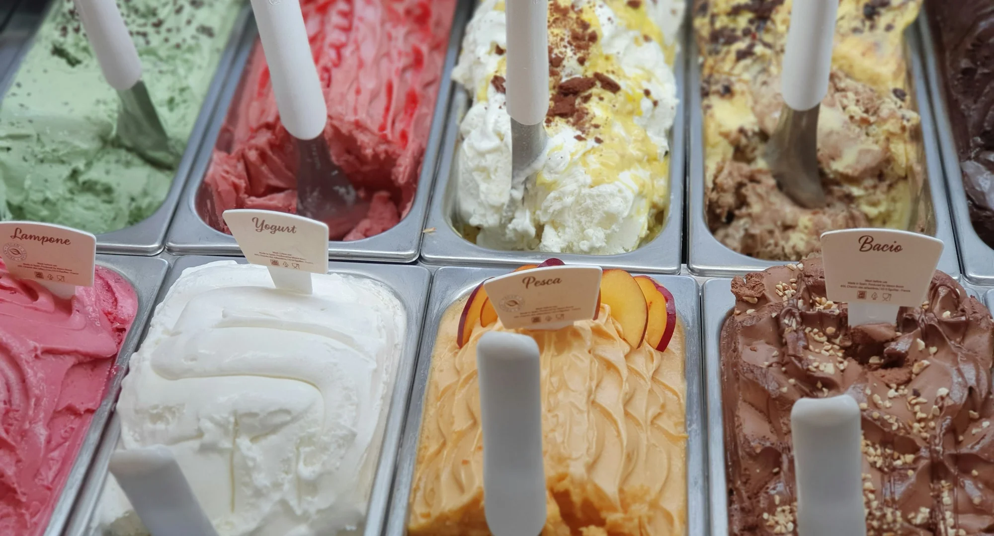 Comptoir de glacier artisanal : bacs de glaces et sorbets variés — pistache, framboise, vanille, citron, pêche, chocolat — servis chez La Dune Glacée à Montalivet